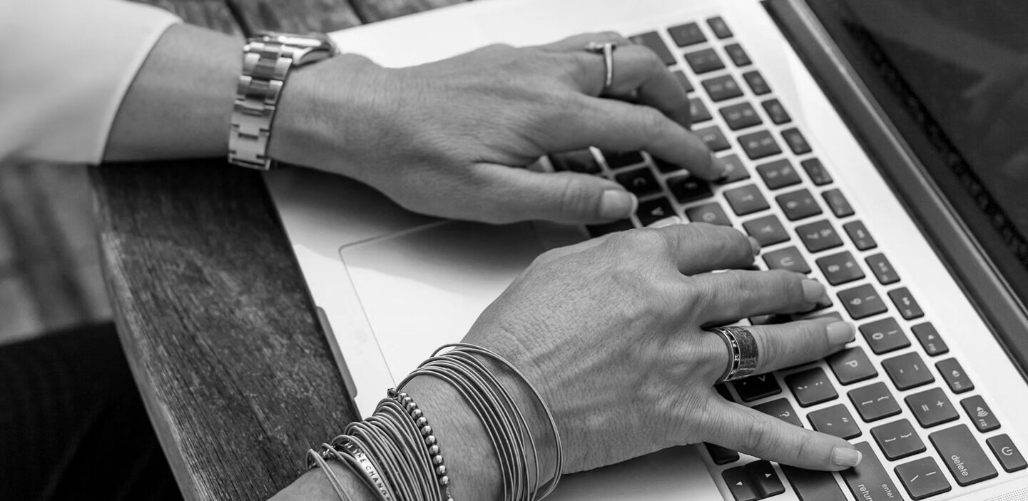 Hands typing on a laptop keyboard to represent using technology