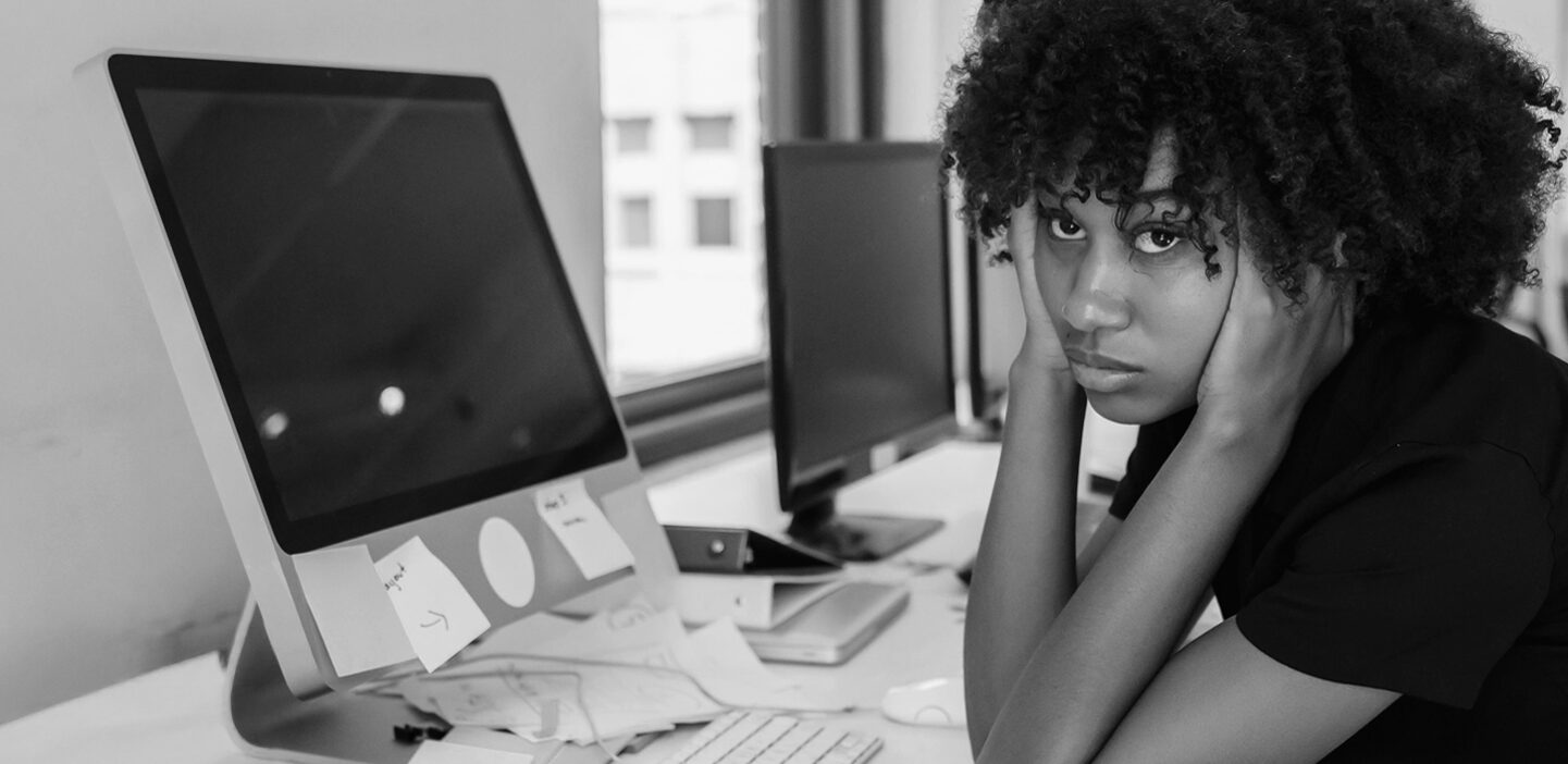 Confused and frustrated woman sitting at her computer, head in hands