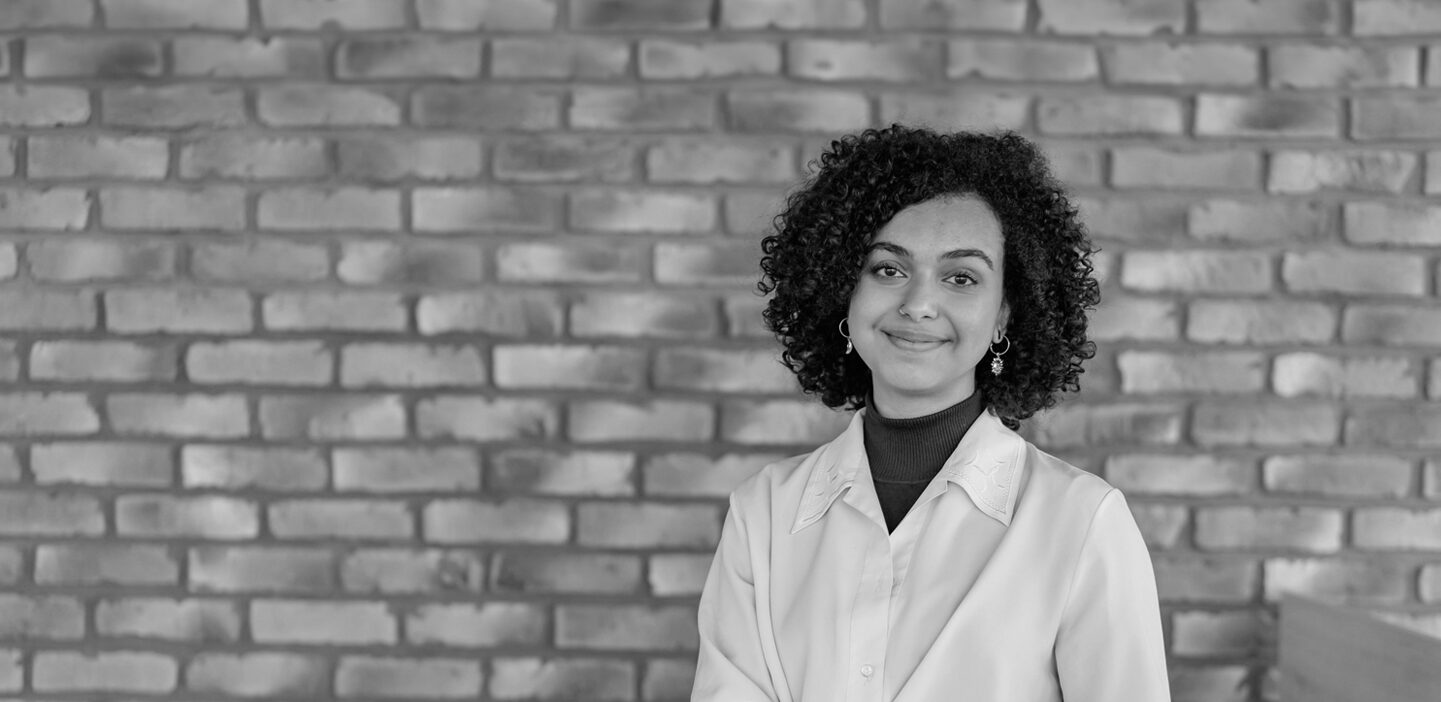 Young woman smiling in front of a brick wall