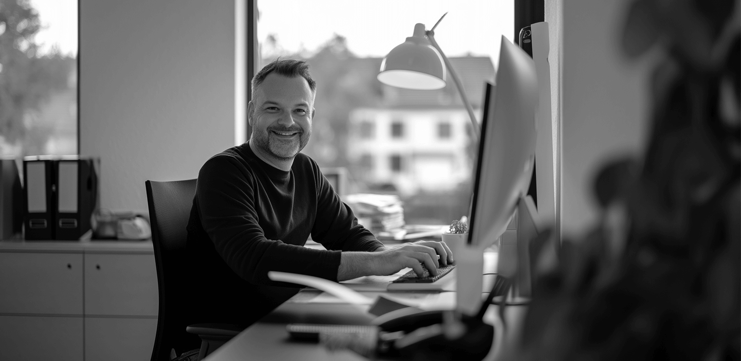 Smiling man seated at his desktop computer