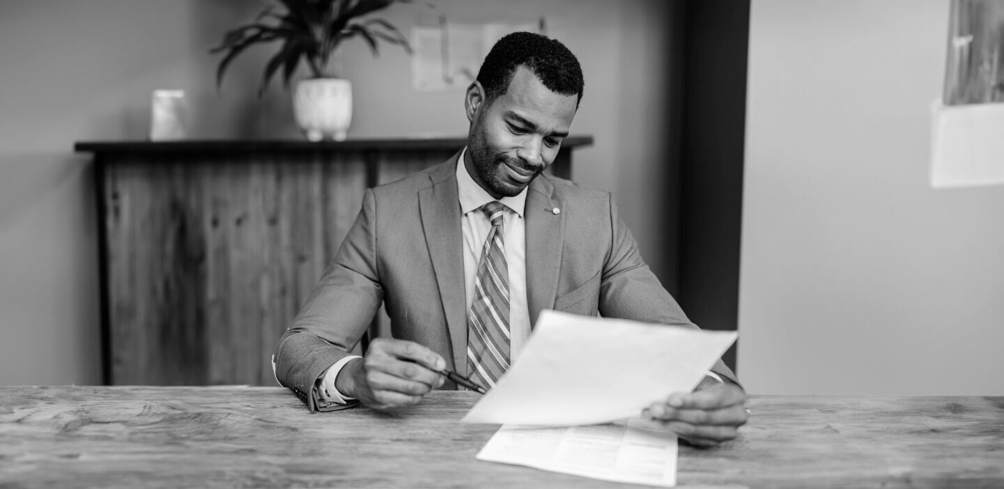 Seated man in suit and tie reviewing business plan to start a software company